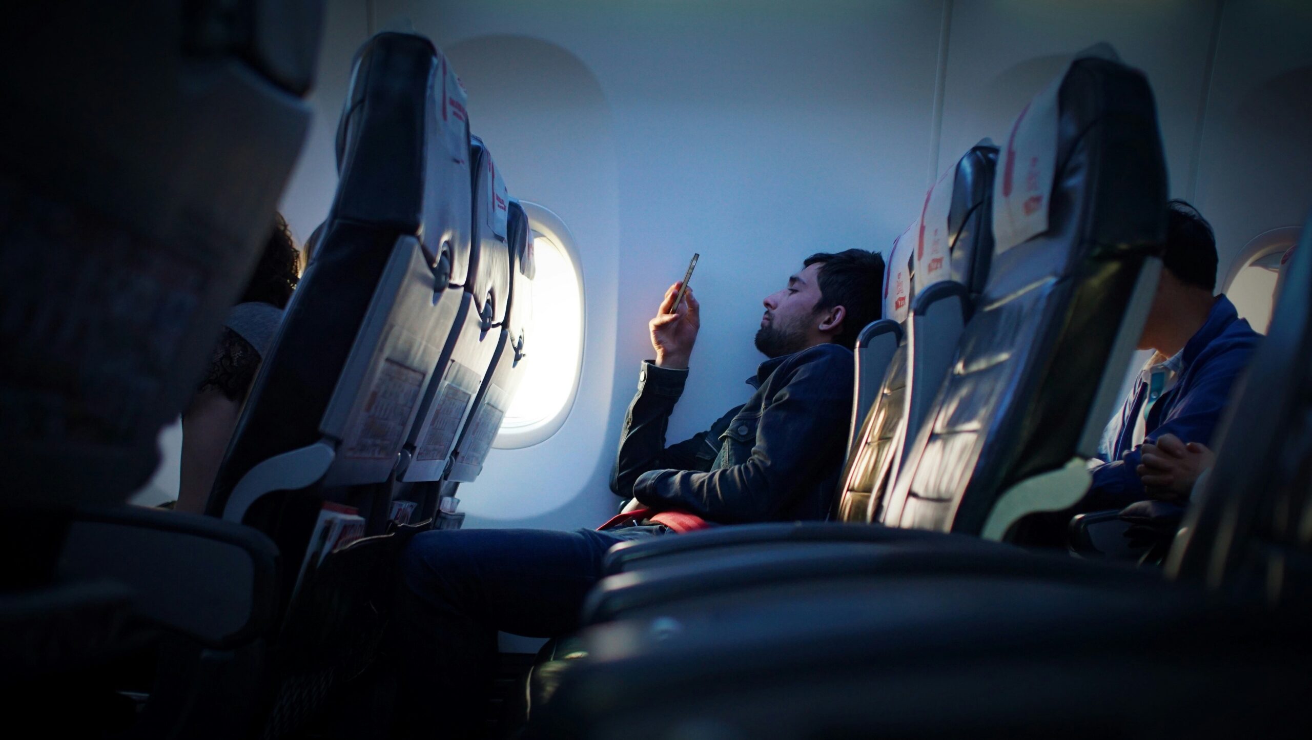 Traveler using a smartphone on an airplane before an international trip