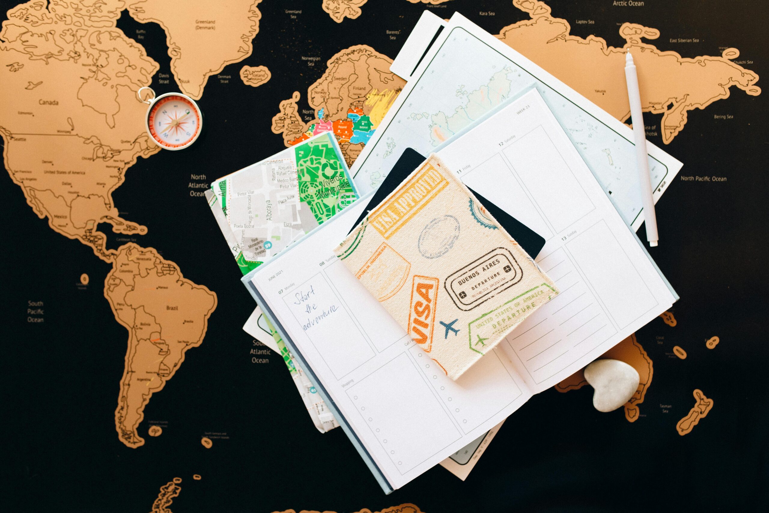 Travel planning items on a world map, including a travel wallet, planner pages, local maps, a compass, and a pen